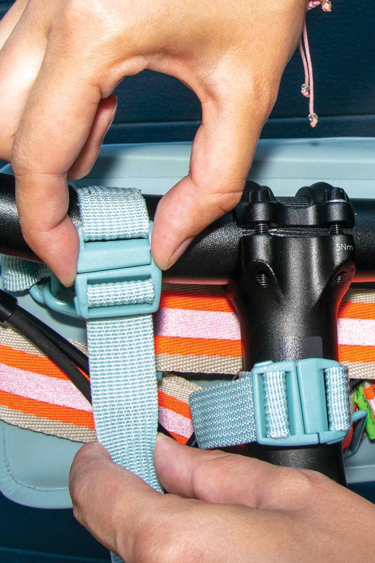 Person adjusting a strap on a bag with colorful stripes