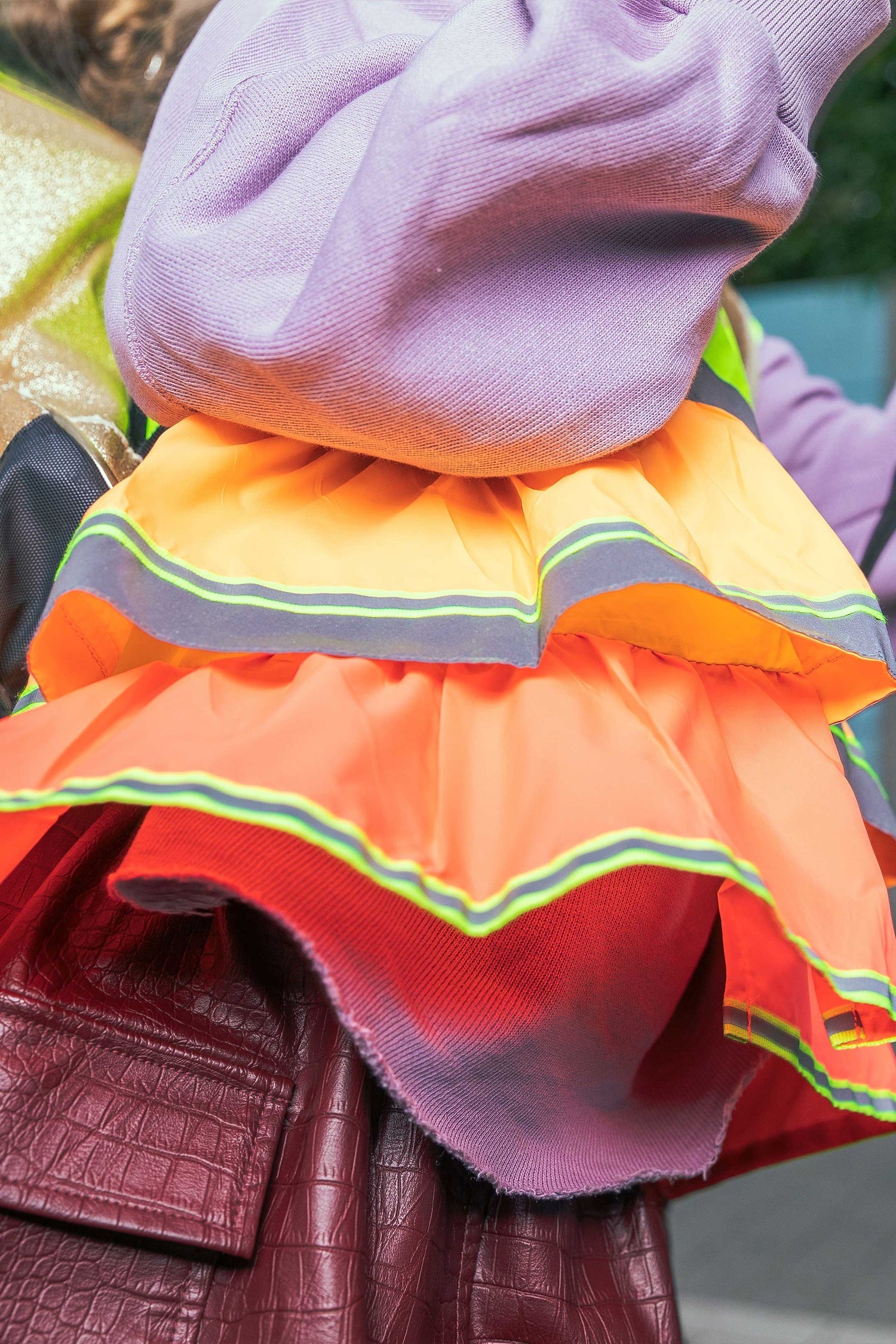 Close-up of a colorful skirt with reflective stripes worn over a purple top.