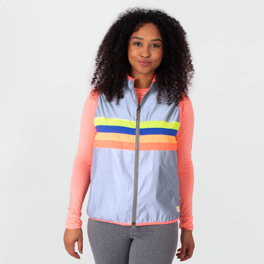 Woman wearing a colorful striped vest over a pink long-sleeve shirt on a white background