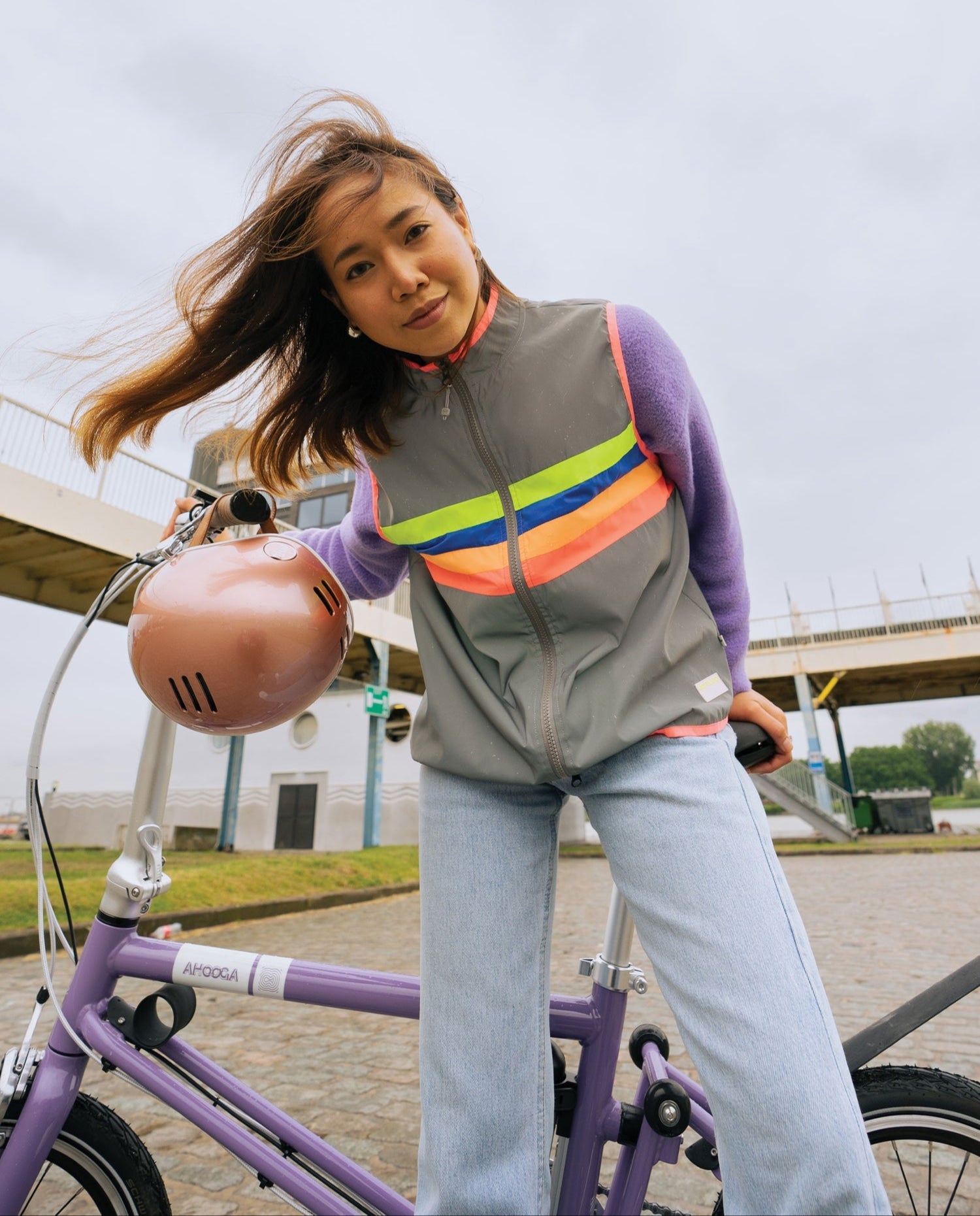 Person wearing a reflective safety vest standing next to a bicycle outdoors.