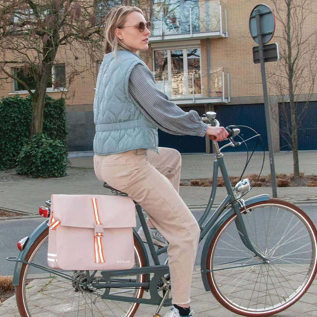 Woman riding a bicycle with a pink bag on a city street