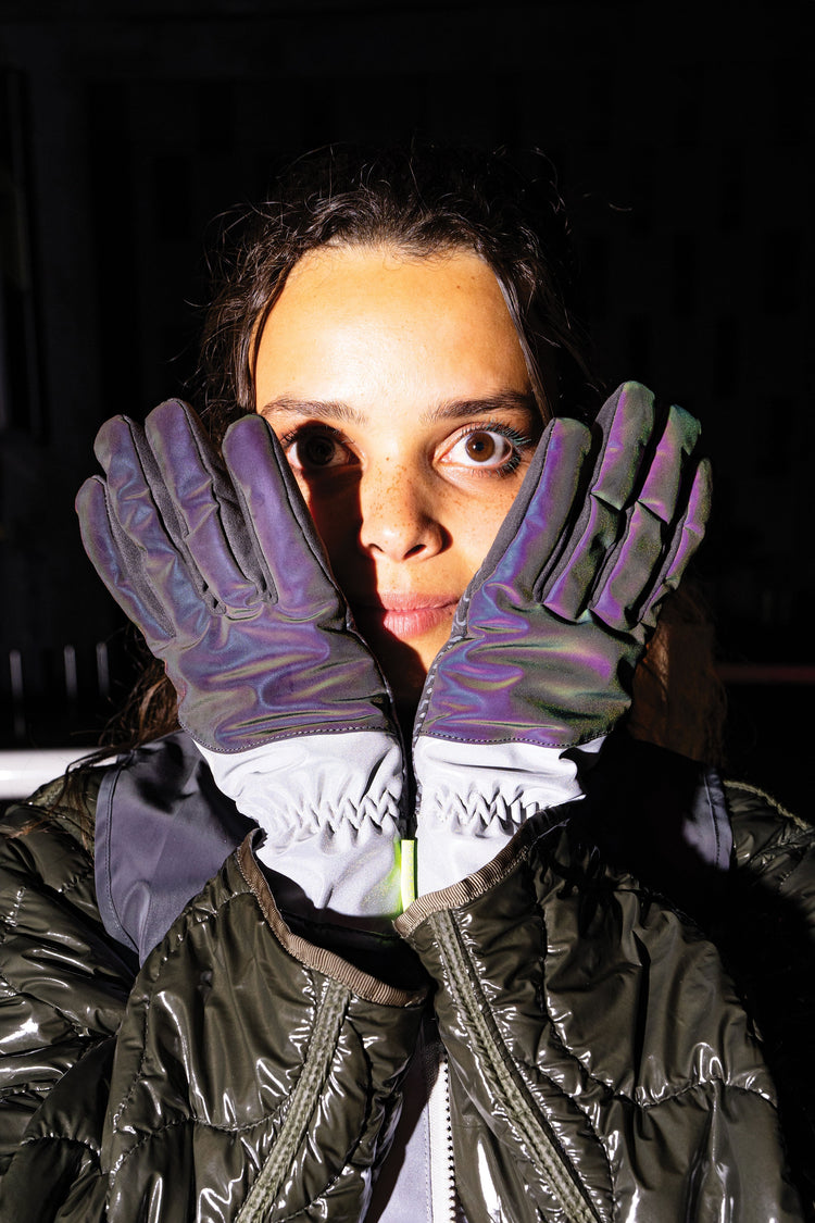 Person wearing reflective gloves and jacket in a dark setting