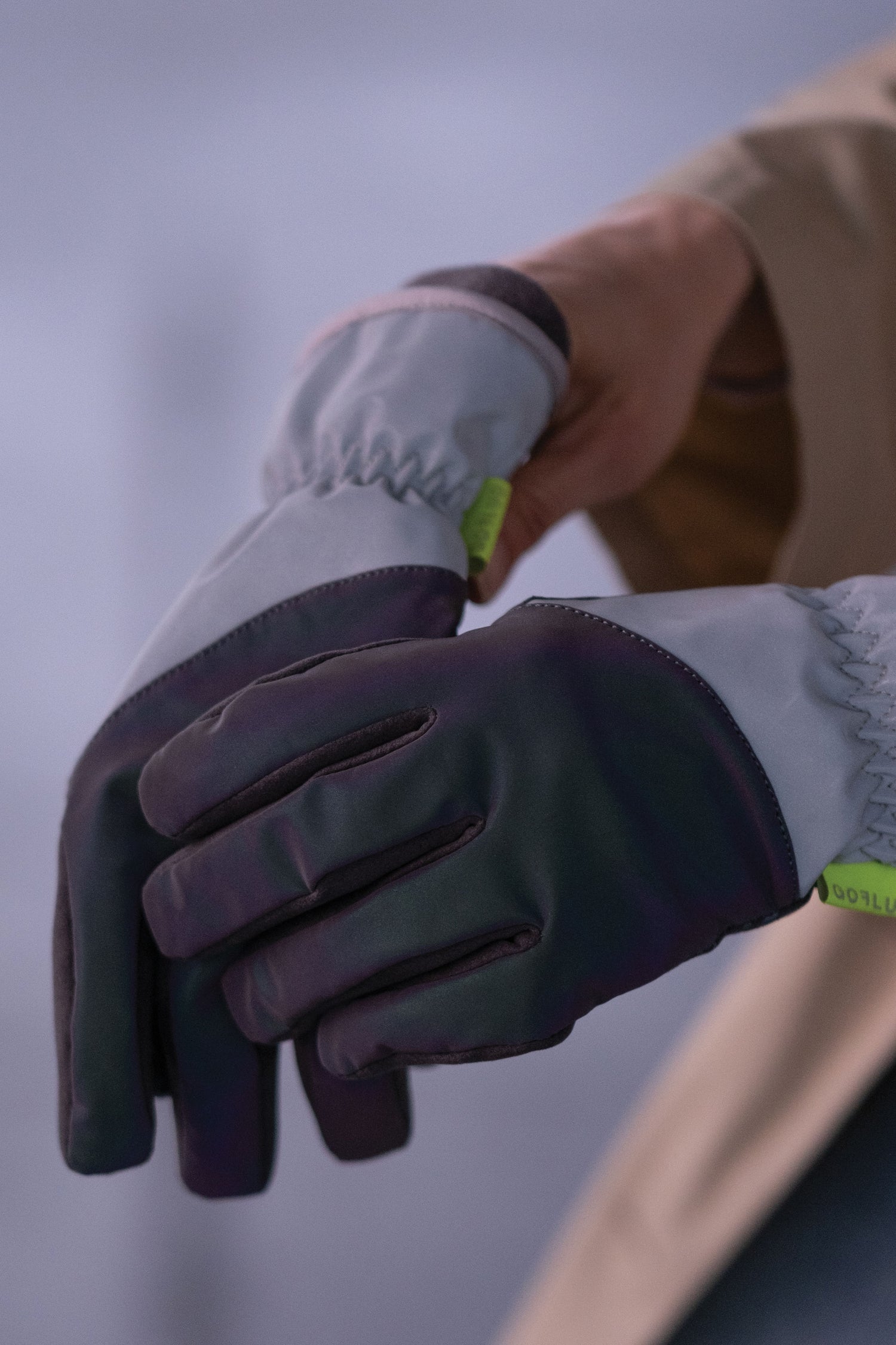 Close-up of hands wearing white and purple gloves with a blurred background