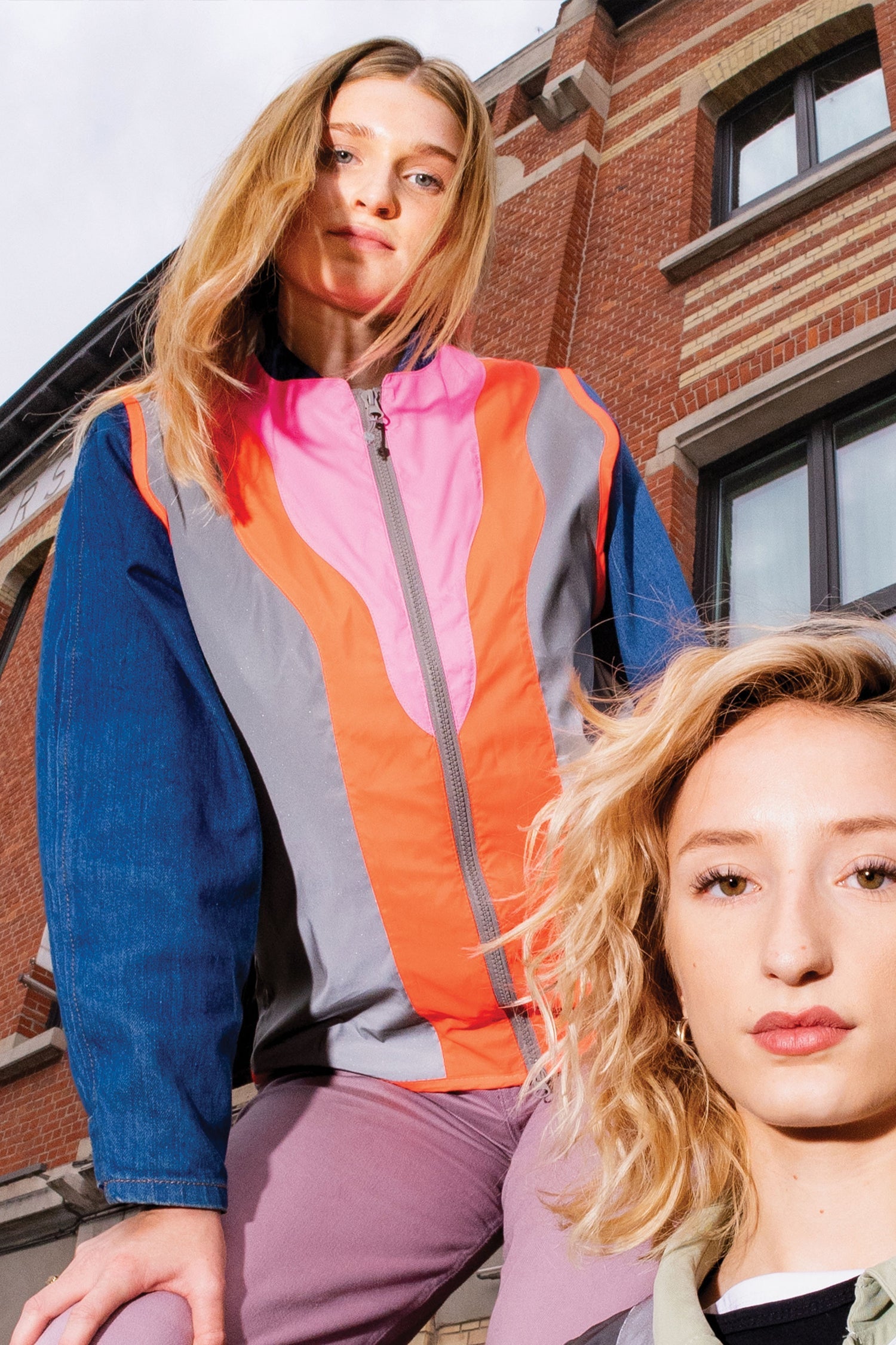 Two women standing outdoors with a brick building in the background