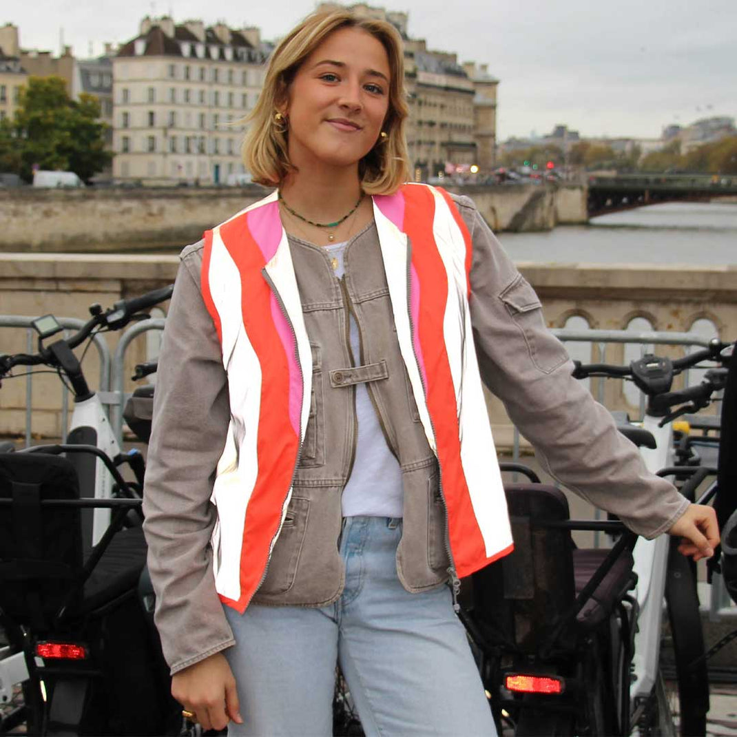 Woman wearing a colorful striped jacket standing on a bridge with a cityscape background