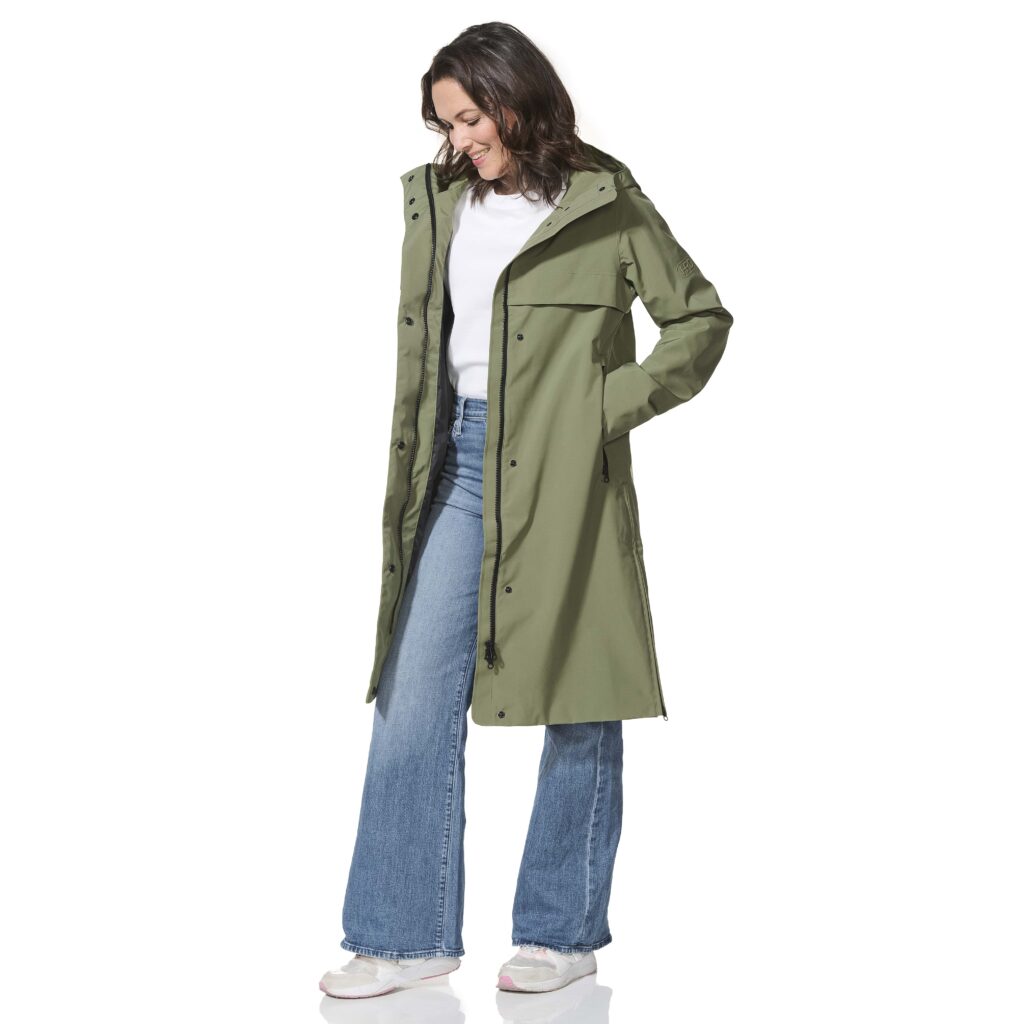 Woman wearing a green trench coat, white shirt, and blue jeans on a white background