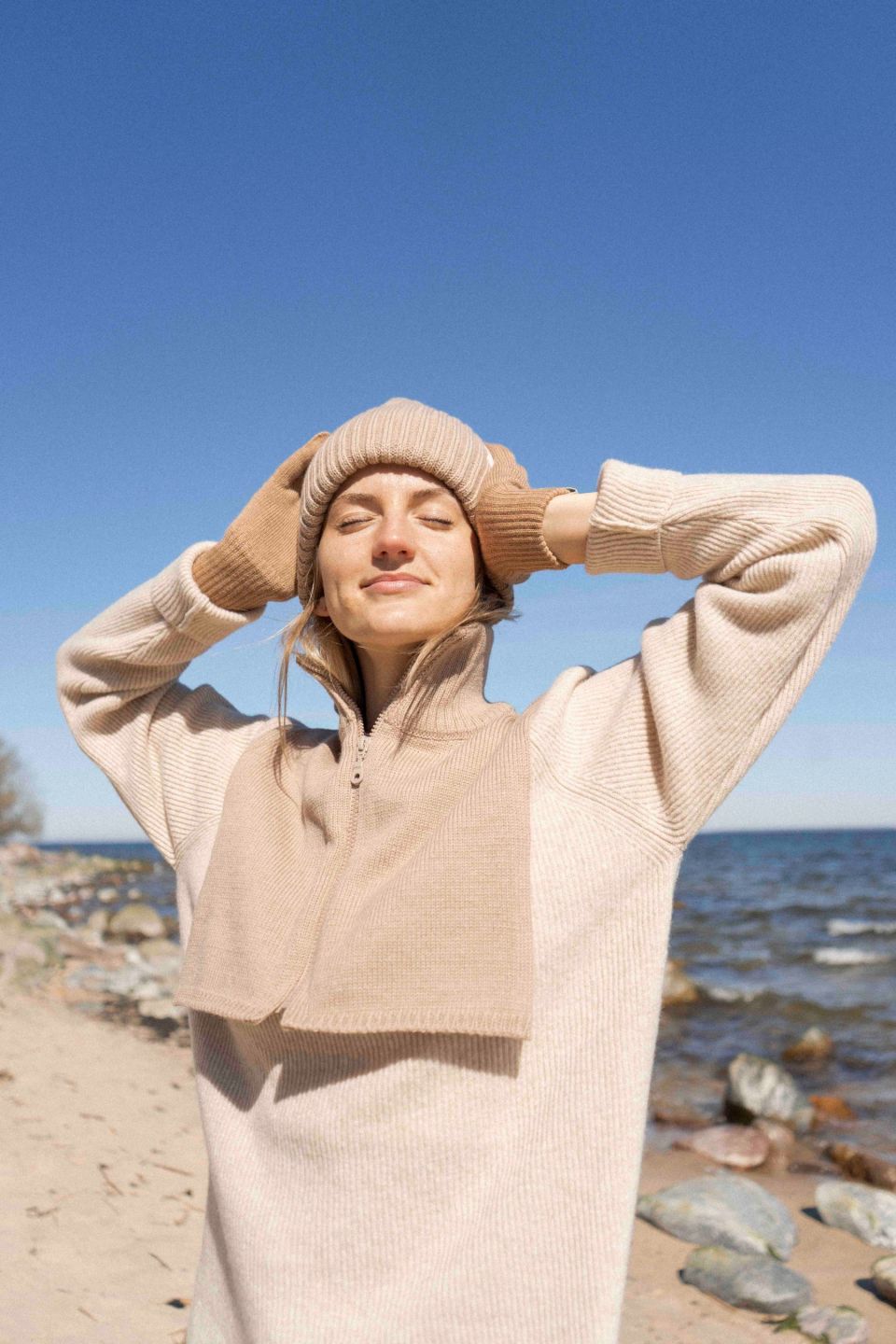 Person wearing a beige outfit on a beach with clear blue sky