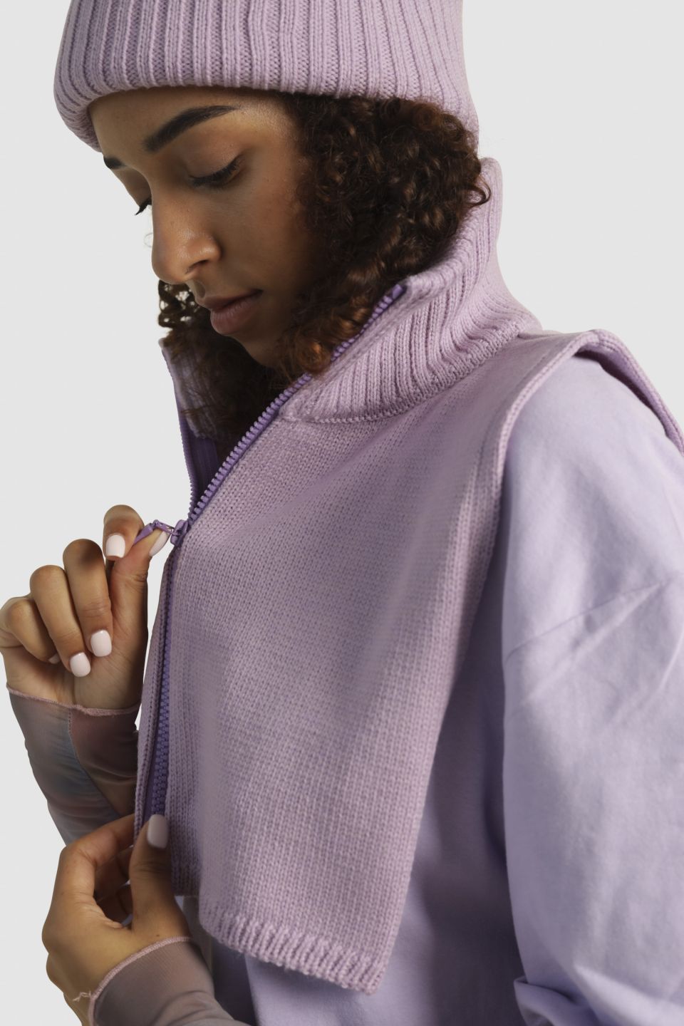 Person wearing a light purple knit  snoodand matching beanie against a plain background